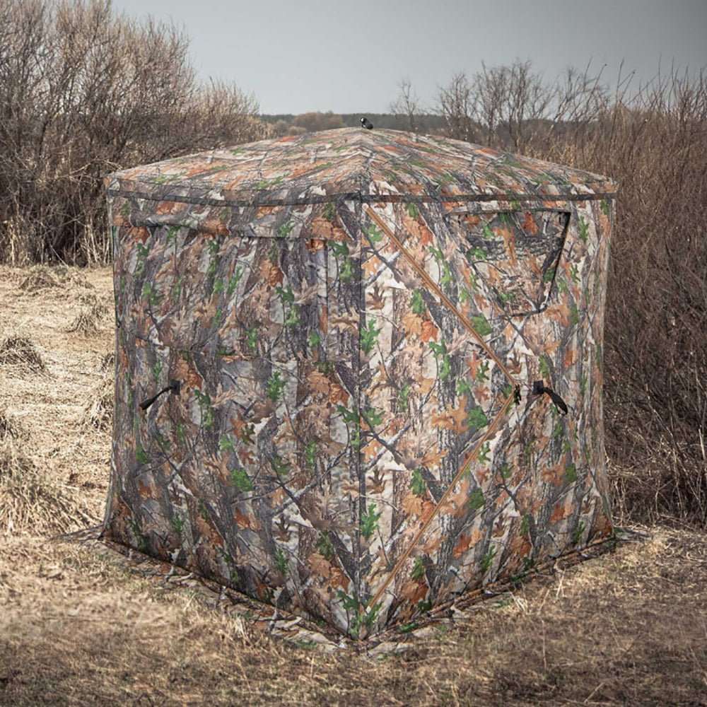 Portable pop up hunting blind tent with camouflage pattern and storage pocket, featuring rust-resistant fiberglass frame and multiple see-through windows for all-weather concealment